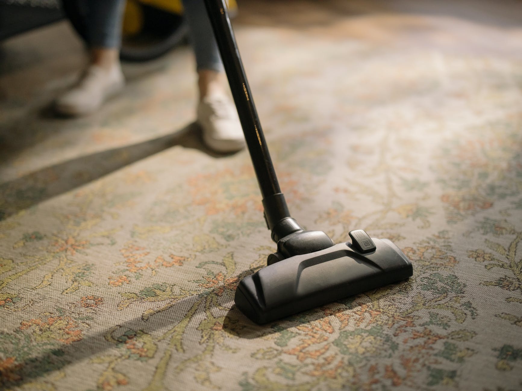 black vacuum cleaner on brown and white area rug