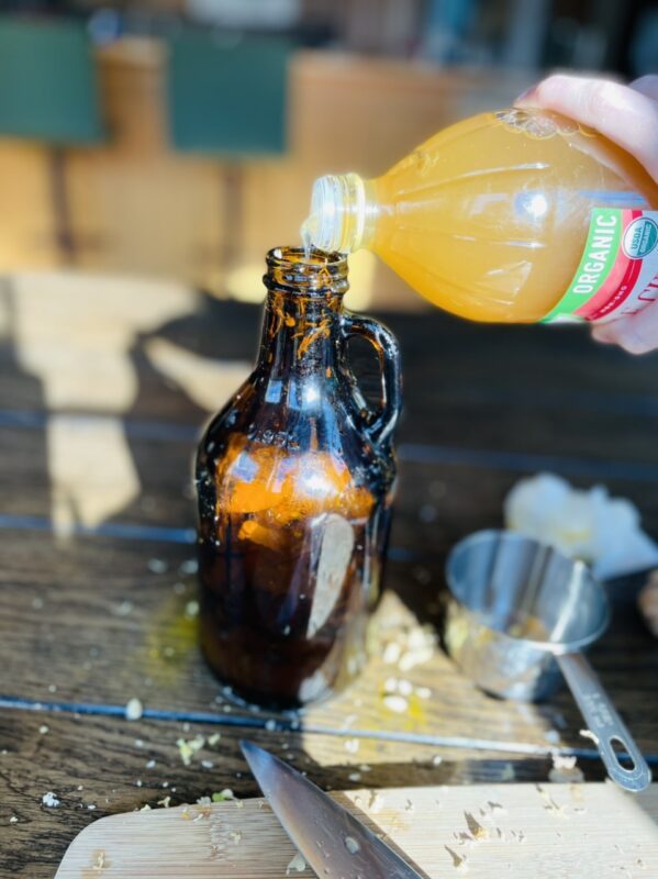 pouring apple cider in an amber bottle