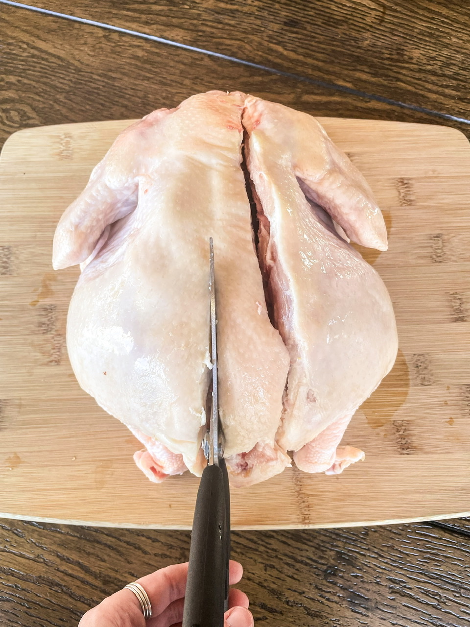cutting out the spine of a raw chicken