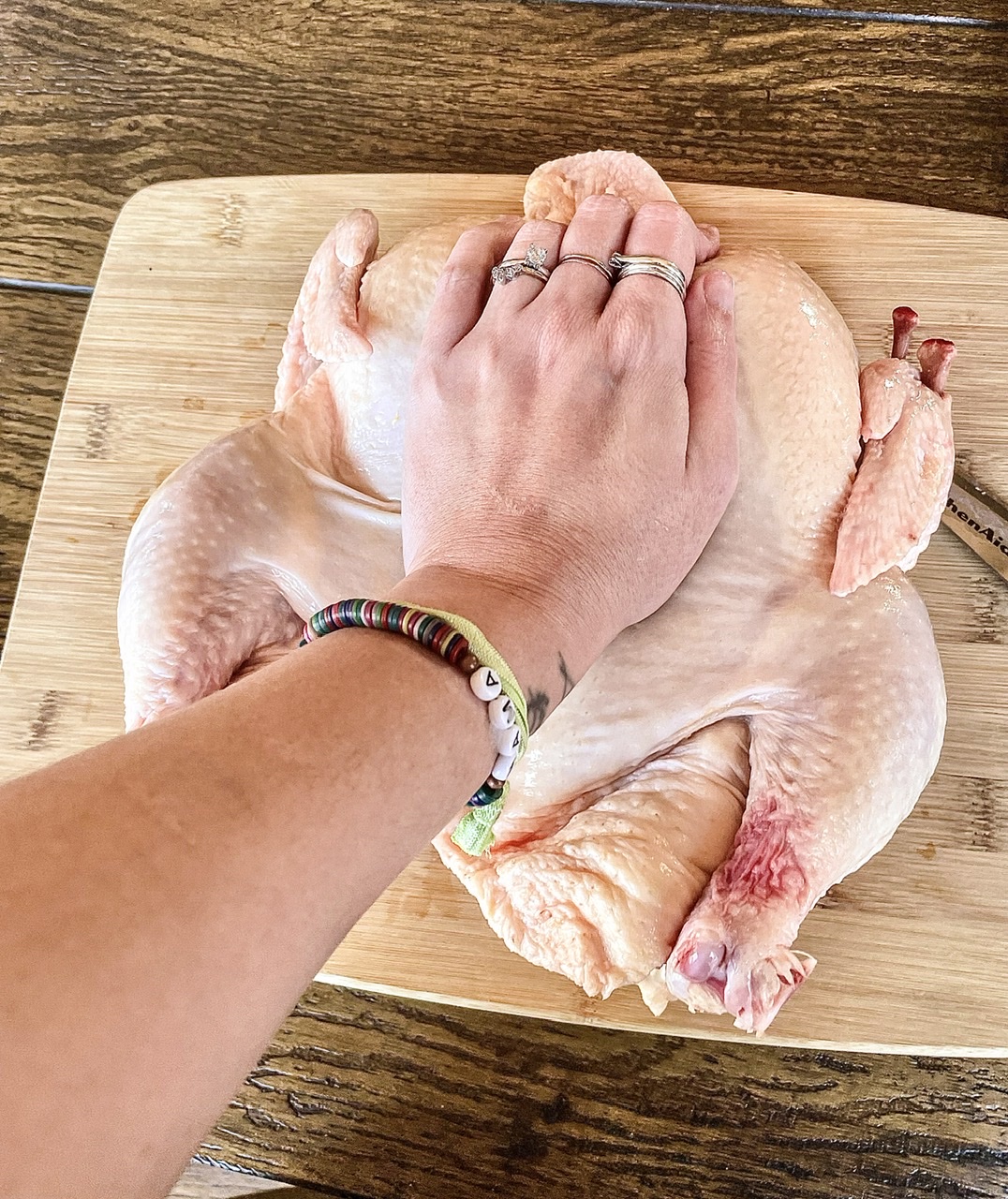 hand putting pressure on chest of raw chicken