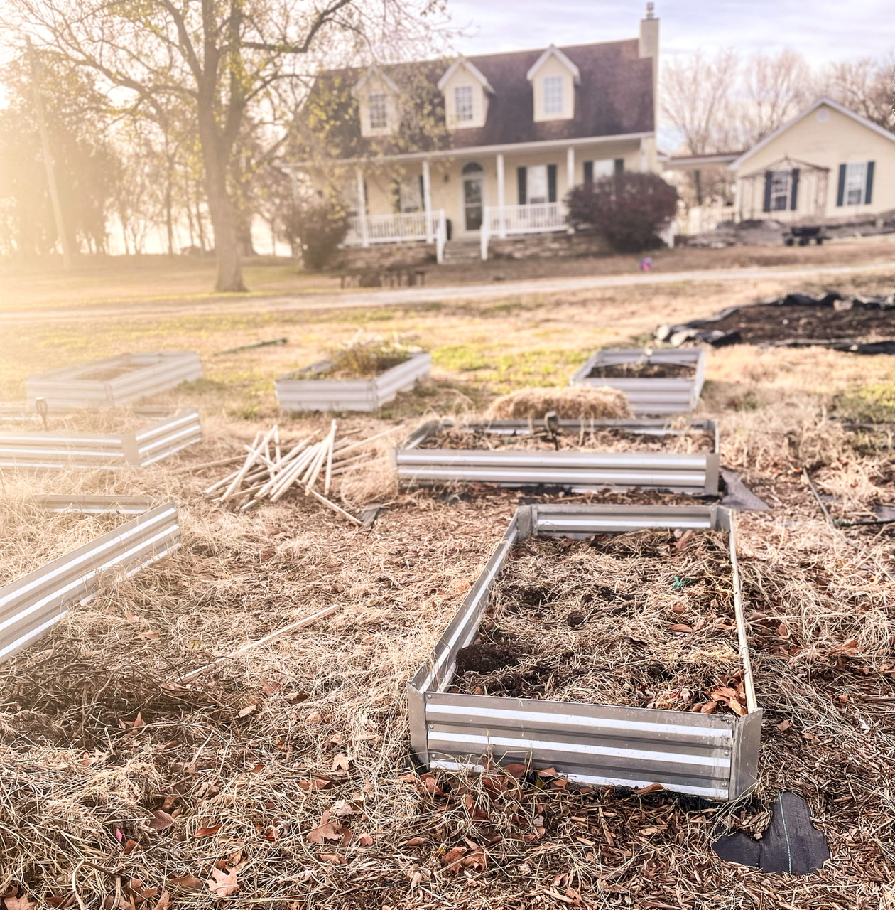 Empty garden bed with yellow house in the background