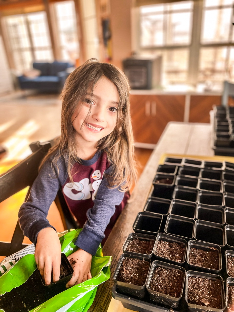 Little girl starting seeds indoors at a table